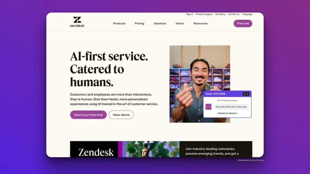 A webpage for Zendesk is displayed with the headline "AI-first service. Catered to humans." It showcases their ai customer support software with options to "Start your free trial" and "View demo." An image of a person pointing and a chat box interaction is shown against a purple background, with navigation links at the top.